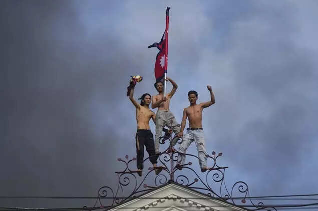 Protesters celebrate standing at the top of the Singha Durbar, the seat of Nepal's government's various ministries and offices, after it was set on fire during protest in Kathmandu, Nepal, Tuesday, September 9, 2025. (AP)