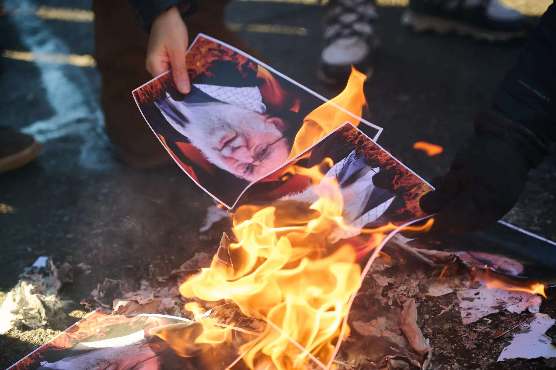 Protesters burn pictures of Iranian Supreme Leader Ayatollah Ali Khamenei as they march in support of regime change in Iran during a protest in Toronto, on Sunday, Feb. 1, 2026. (Sammy Kogan/The Canadian Press via AP) Canada Iran Protest