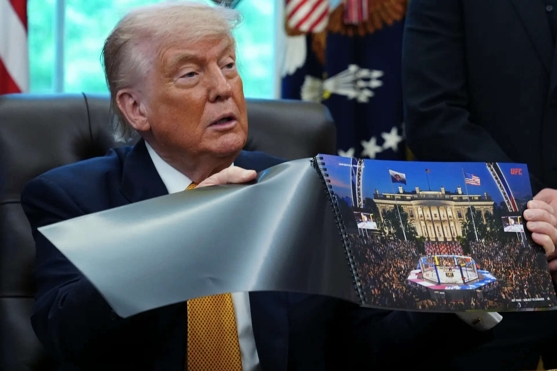 President Donald Trump holds up an image depicting a preview of the Trump