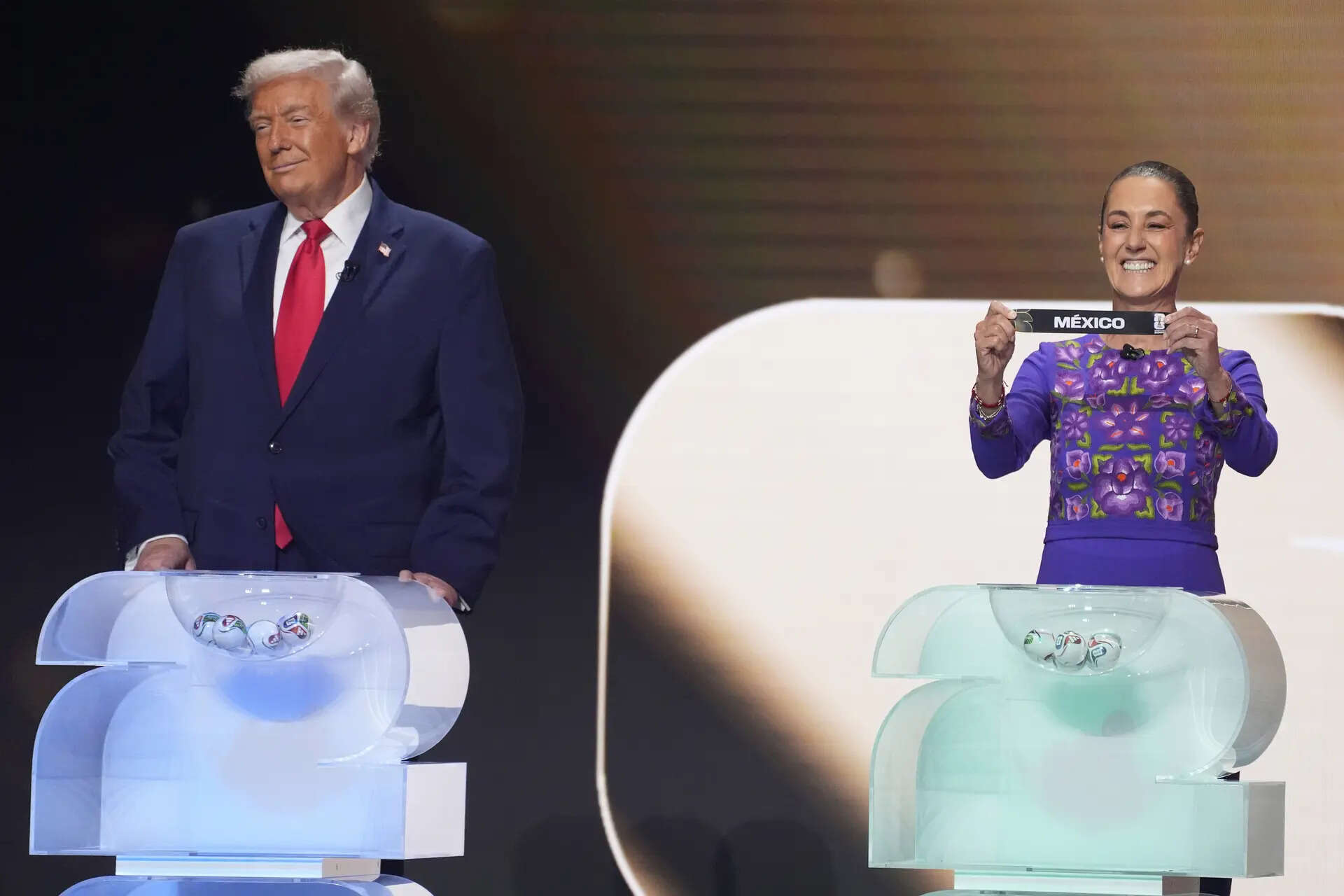 Mexican President Claudia Sheinbaum holds up the team name of Mexico as President Donald Trump, left, looks on during the draw for the 2026 soccer World Cup at the Kennedy Center in Washington, Friday, Dec. 5, 2025.(AP Photo/Evan Vucci) WCup Draw Soccer Trump